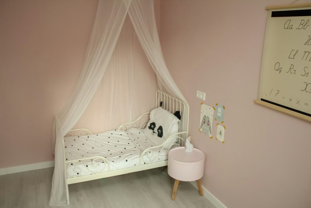Chambre d’enfant avec un lit à baldaquin et une petite veilleuse posée sur la table de chevet